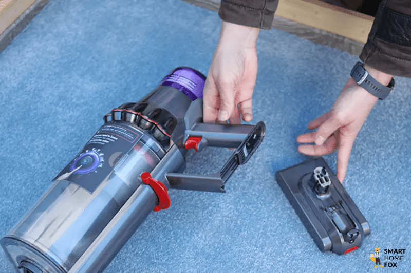 Der Akku eines Dyson Akkustaubsaugers liegt auf dem Teppich